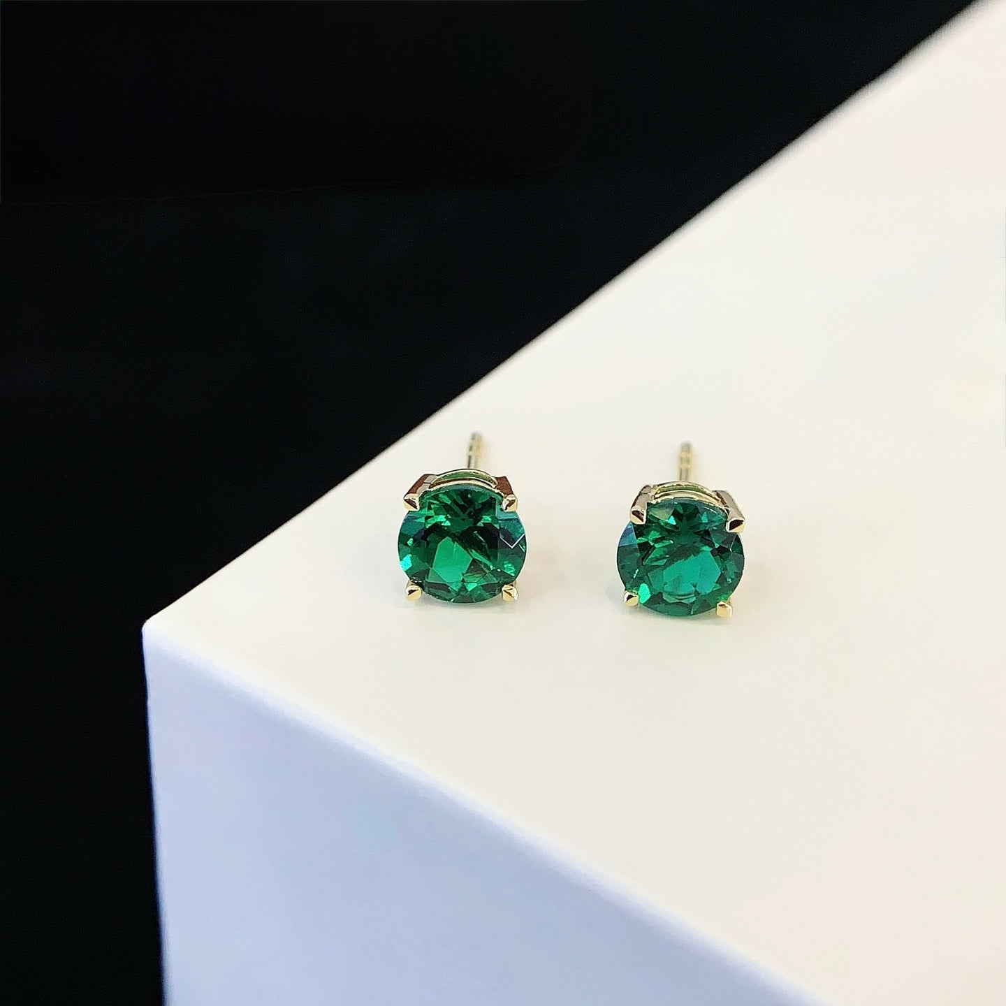 Round cut emerald stone earrings.